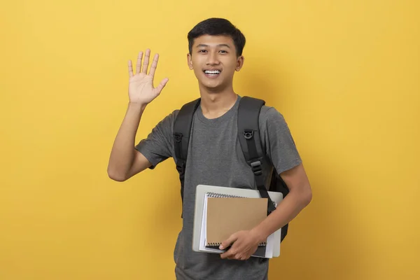 Sırt Çantası Kitaplarıyla Gülümseyen Genç Üniversite Öğrencisi Sarı Arka Planda — Stok fotoğraf