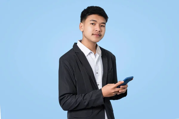 Mladý Pohledný Asijský Podnikatel Úsměvem Pomocí Smartphone Ruce Izolované Modrém — Stock fotografie