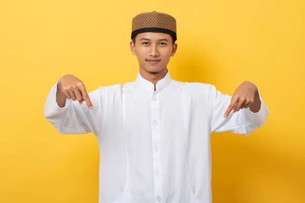 年轻英俊的亚裔穆斯林男子站在橙色的背景上 手指朝下 — 图库照片