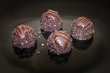 Luxurious chocolate truffles. Pralines designed in Belgium and arranged on the table. Chocolate Candies and pralines of 4 pieces arranged on a dark background. 