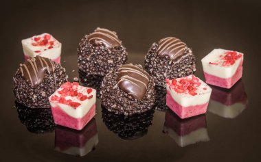 Luxurious mixed colorful chocolate praline. Strawberry, coconut, vanilla and lemon truffles. Pralines designed in Belgium and arranged on dark background. Chocolates selection. Truffles and pralines for Wedding day.