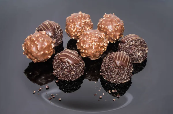 Luxurious sweets chocolate truffles. Pralines designed in Belgium and arranged on the table. Candies on a dark background. Assortment sweet confectionery of dark and milk chocolate with nuts.