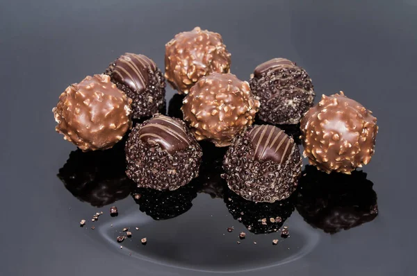 Luxurious sweets chocolate truffles. Pralines designed in Belgium and arranged on the table. Candies on a dark background. Assortment sweet confectionery of dark and milk chocolate with nuts.