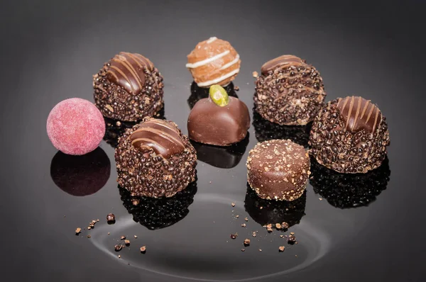 Luxurious handmade chocolate truffles. Pralines designed in Belgium and arranged on the black table. Chocolate candies on a dark background. Assortment sweet confectionery.