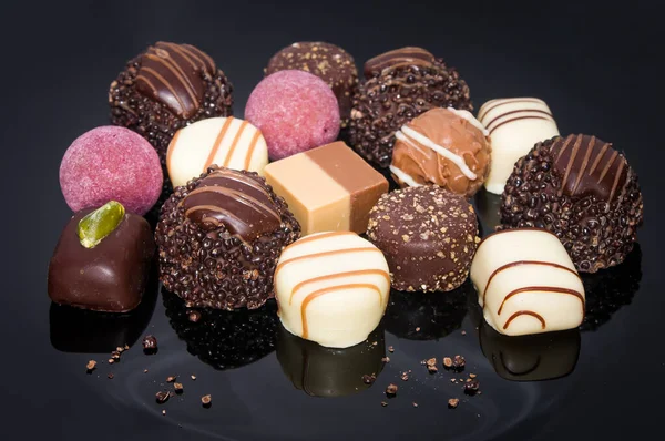 Luxurious mixed colorful handmade chocolate praline. Variety of strawberry, coconut, vanilla and lemon truffles. Pralines designed in Belgium and arranged on dark background. Assortment sweet confectionery.