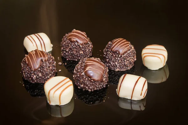 Selection truffles and pralines confection for Birthday present. Chocolate candies and luxury pralines in dark background. Assortment of dark, white and milk chocolate with nuts.