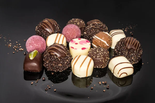 Luxurious mixed colorful handmade chocolate praline. Variety of strawberry, coconut, vanilla and lemon truffles. Pralines designed in Belgium and arranged on dark background. Chocolates selection. Truffles and pralines for Wedding day.