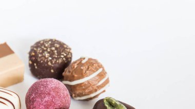 Chocolate pralines truffles with empty space for text. Selection round truffles confection design for Birthday gift. Luxury candies in white background. Assortment of colorful milk chocolate with nuts.