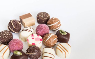 Chocolate pralines truffles with empty space for text. Selection round truffles confection design for Birthday gift. Luxury candies in white background. Assortment of colorful milk chocolate with nuts.