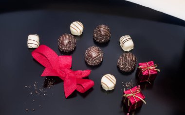 Chocolate and red tied bow on table with two small props Christmas square box gift. Christmas festive decoration.