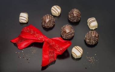 Chocolate pralines truffles decorated with red tied sparklin bow. Confection.