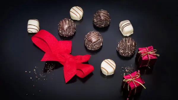 Four piece white and 4 piece brown chocolate truffles and decorative red bow.