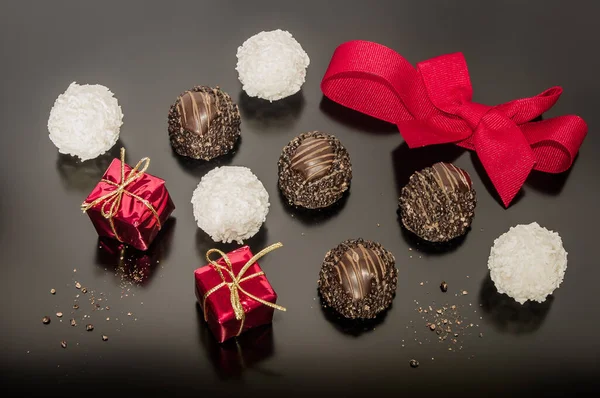 Variation of chocolate pralines with hazelnuts and coconut balls for Christmas day with red tied ribbon. Two small Christmas square box. Festive decoration.