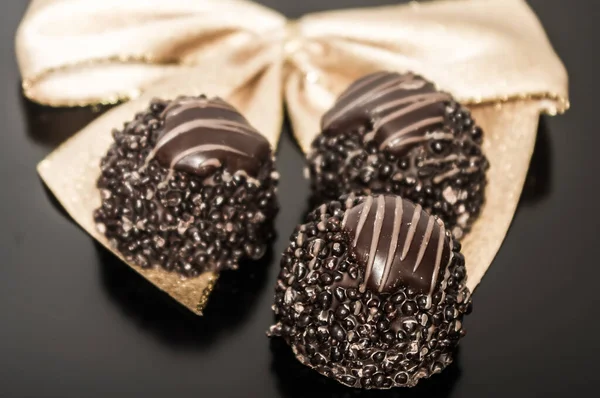 Three pieces of chocolate truffles with gold ribbon background.