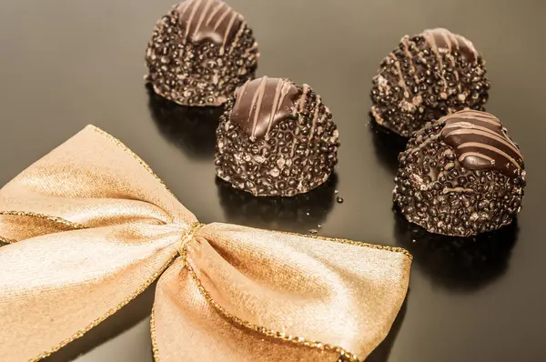 Four pieces of chocolate truffles with gold ribbon background.