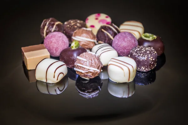 Luxurious mixed colorful handmade chocolate praline. Variety of strawberry, coconut, vanilla and lemon truffles. Pralines designed in Belgium and arranged on dark background. Chocolate truffle with nuts.