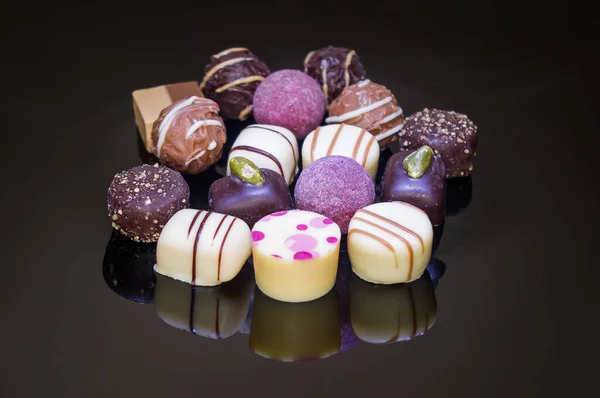 Chocolate candies and pralines with ornaments and sprinkles. Colorful variety of strawberry, coconut, vanilla, chocolate nuts and lemon truffles.