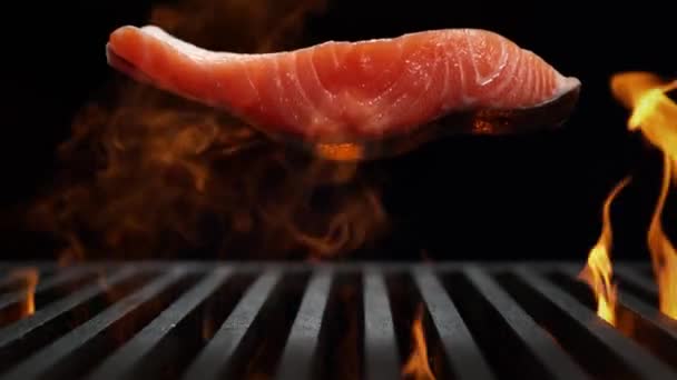 鲑鱼片慢动作落在烤架上燃烧 黑色背景下的烧烤 — 图库视频影像