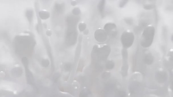 スローモーションとマクロでのミルクスプラッシング アブストラクトホワイトエネルギー的に弾む流体が液滴とスプラッシュを作る — ストック動画