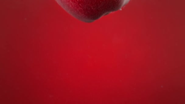 Яблуко Падає Воду Робить Повітряні Бульбашки Повільними Червоному Фоні — стокове відео