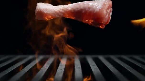 慢动作生鸡腿落在烤板条板上燃烧 黑色背景烤肉 — 图库视频影像