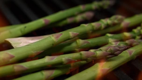 スローモーションでグリルグレートフレーミング上の緑のアスパラガス バーベキュー野菜と火のマクロドリーショット — ストック動画