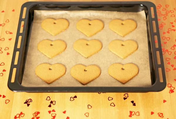 Romantic heart cookies on a baking sheet on the table with many red hearts decorations. Valentines or mothers day. High quality photo.