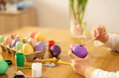 Çocuk eller evdeki ahşap masaya renkli Paskalya yumurtası boyuyor. Mutlu Paskalyalar. Paskalya kutlaması için hazırlık. Yüksek kalite fotoğraf.