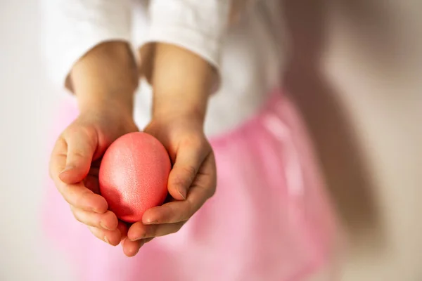 Pembe kaya ve beyaz gömlekli bir kız elinde pembe bir Paskalya yumurtası tutuyor. Mutlu Paskalyalar. Paskalya ve bahar için hazırlık. Yüksek kalite fotoğraf.