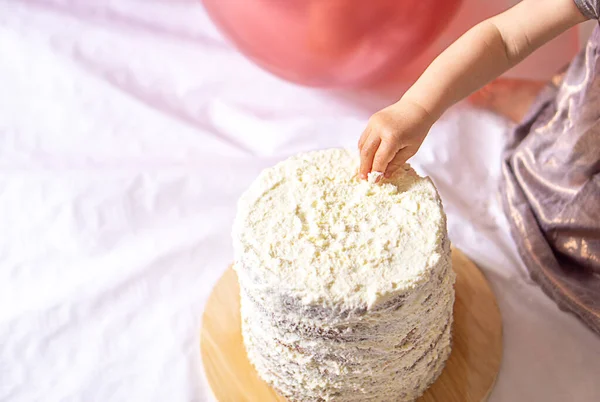 Küçük kızın eli ilk doğum günü kutlaması için nefis bir pastayı eziyor. Yüksek kalite fotoğraf