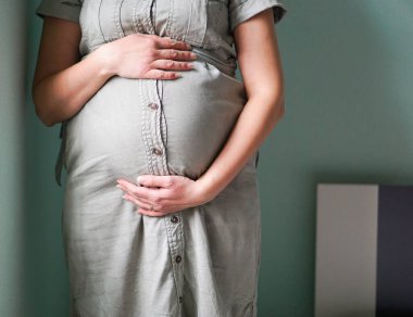 Hamile bir kadının güzel, koca göbeğini kapat. Hamilelik, beklenti ve annelik kavramı. Genç hamile kızın yan bakışı. Hamile kadın kendini evinde mutlu hissediyor.