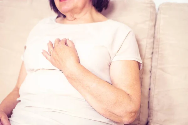 stock image Close up of old female hand holding her chest. Health problem, old age and people concept. Middle aged woman holding breast because of heart infraction at home. Senior woman feeling heart pain.