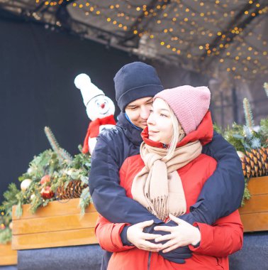 Mutlu kız ve oğlan bir kış günü Noel süslemesi önünde sarılıyorlar. Yüksek kalite fotoğraf