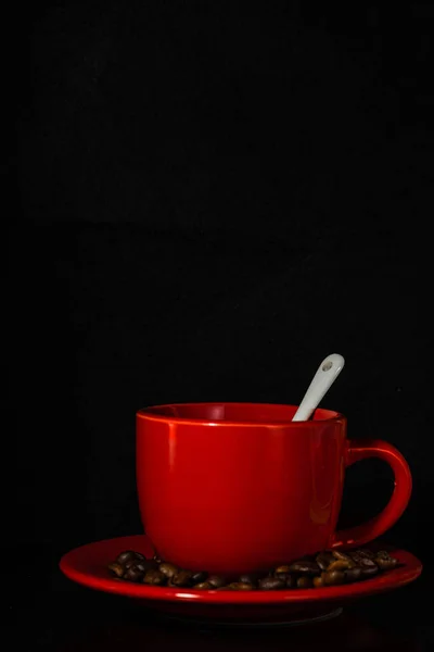 Siyah arka planda beyaz kaşıklı parlak kırmızı bir kupa. Yüksek kalite fotoğraf