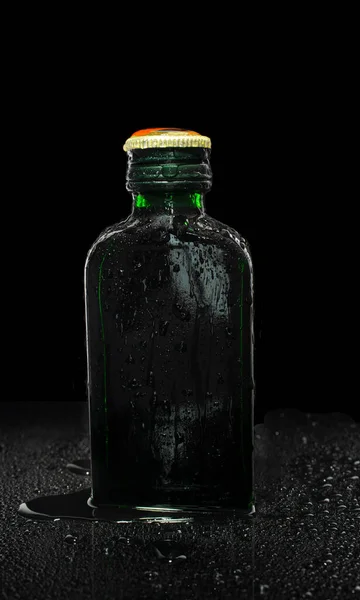 small green glass bottle on black background. High quality photo