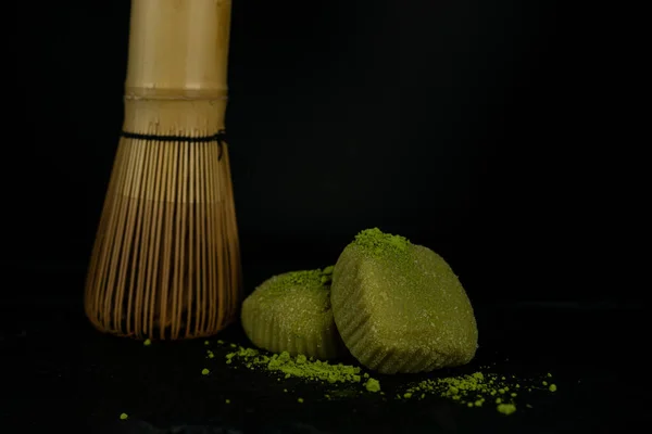 Chasena 'nın yan tarafında siyah bir zemin üzerinde yeşil çay bulunan iki parça mochi. Yüksek kalite fotoğraf