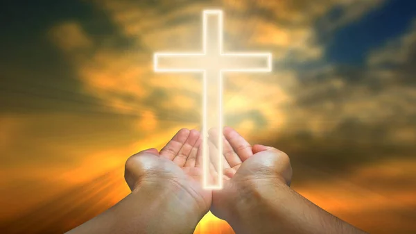 stock image Hands holding christian cross against blue sky with white clouds and sun