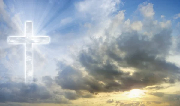 Digital composite of Christian cross with sun flare over blue sky. christian religion concept
