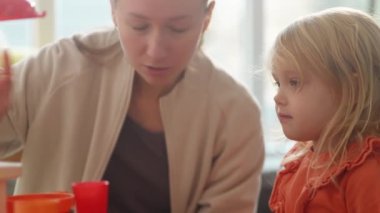 Mother and daughter performing role game about making hot drinks, family time. Bright nursury with kitchen and toy teaset. Happy ladies pretend cafe owning, imaginary food and drinks. HQ 4k footage