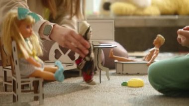 Close up of mothers hands playing with national culture doll and wooden toy furniture, games on the floor, nice artificial interior. Family playtime delight, exploring nationality. HQ 4k footage