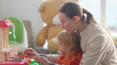 Mother and daughter performing role game about cooking breakfast, family time.Bright nursury with toy kitchen and toy teaset.Happy ladies preparing imaginary food and drinks. Dishes and utencils.HQ 4k