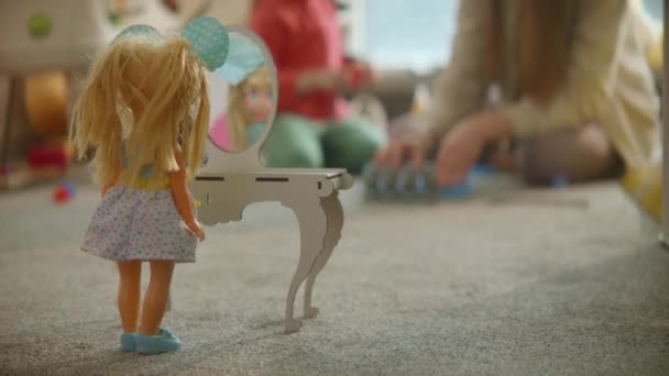 おもちゃのテーブルミラーに立って人形は 母親と娘が保育室の背景 素敵なカジュアルなインテリア 床の上のゲームで一緒に遊んでいます — ストック動画