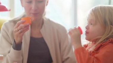 Anne ve kız, sıcak ve soğuk içecekler yapmak ve tatmakla ilgili rol yapma oyunu oynuyorlar. Eğlence zamanı. Mutfak oyuncakları seti olan parlak bir hemşire. Mutlu bayanlar çay partisi ya da sabah kahvesini taklit ederler. Karargah 4k görüntüsü