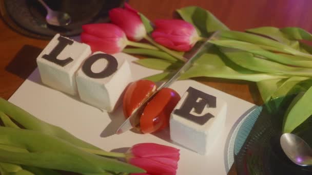 言葉でケーキの背景提供されるテーブルの新鮮なチューリップの間で愛 ナイフカット メッセージとして心の中の壊れた心 バレンタインデーの儀式 予期せぬ驚き 4K映像 — ストック動画