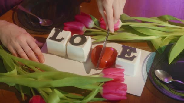 言葉でケーキの背景提供テーブルの上に新鮮なチューリップの間で愛 手は2つの部分で心を切断します ラブメッセージ バレンタインデーのお祝い 予期せぬ驚き 4K映像 — ストック動画