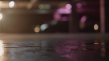 Yer altı otoparkının içinde giden bir arabanın yan görüntüsü, endüstriyel arka ve ön farlar, siyah zarif araba, karanlık sahne, bulanık sahne, bokeh etkisi. Yüksek kalite 4k görüntü