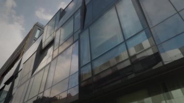 Bulutların alttaki görüntüsü modern ofis binasının büyük cam pencerelerine yansıyor, iyi korunmuş ofis merkezi kompleksine. Mimarlık detayları. Şehir manzarası. Yavaş çekim yüksek kalite 4k görüntü