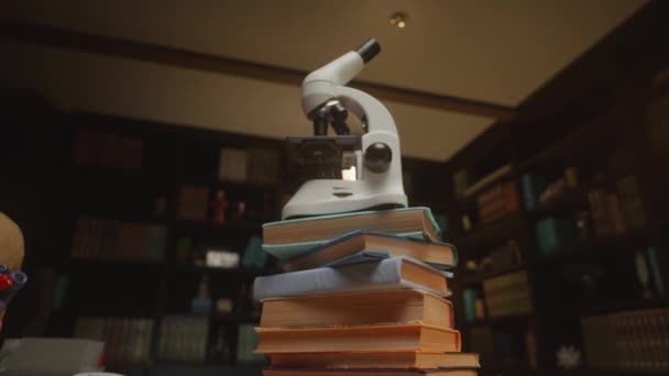 Πλησιάζοντας Ένα Λευκό Σύγχρονο Μικροσκόπιο Στη Βιβλιοθήκη Μια Στοίβα Από — Αρχείο Βίντεο