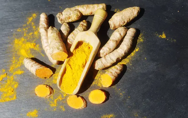 Turmeric powder (Kurkuma) in a wooden spoon and roots 