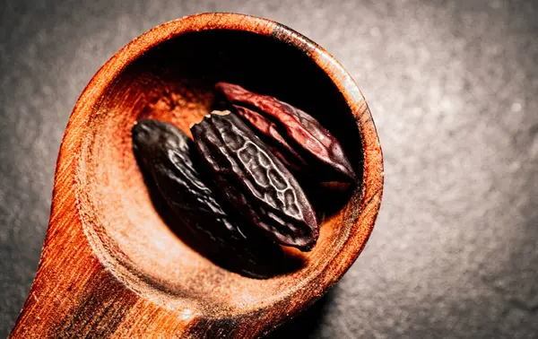 stock image Tonka Beans in a wooden Spoon on a dark background.